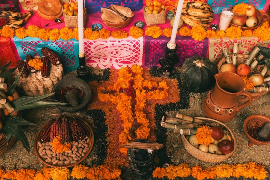 A tiered ofrenda dressed with marigolds, candles and offerings